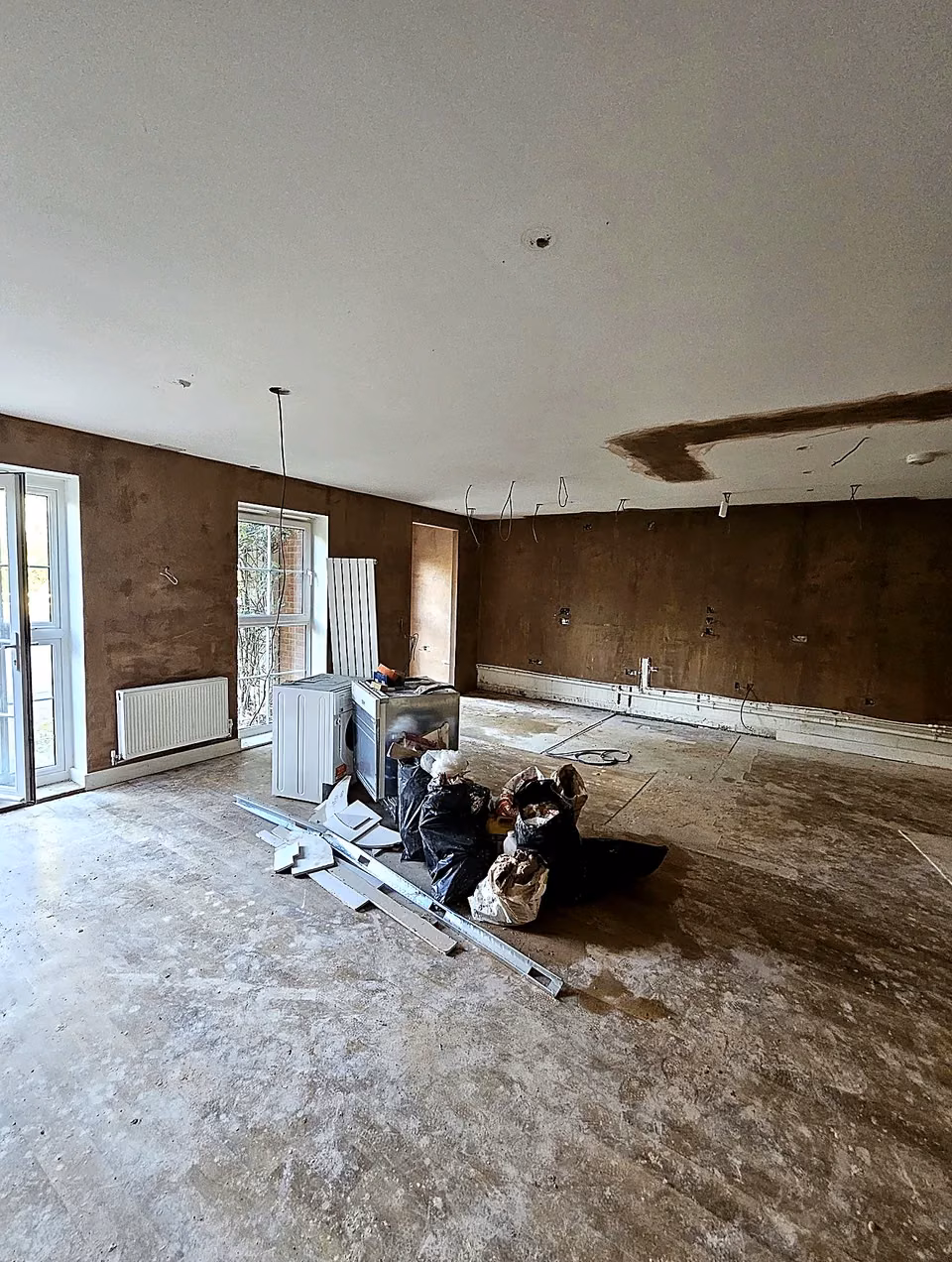 Original residential room with stripped walls and exposed floor before refurbishment