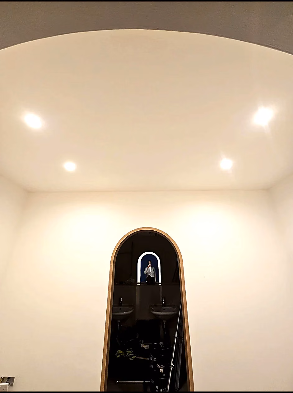 Illuminated recessed ceiling downlights above a room with an arched doorway