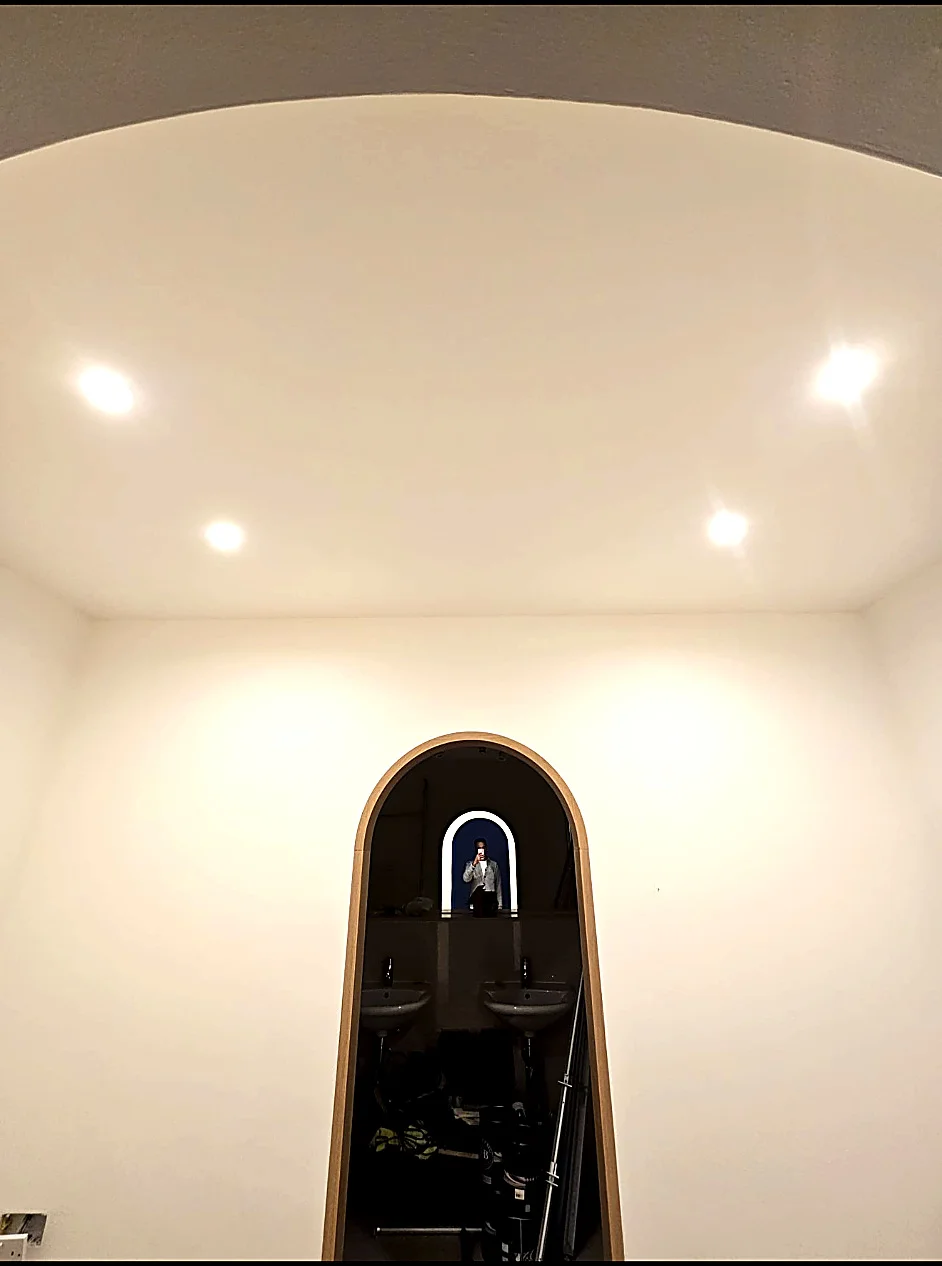 Illuminated recessed ceiling downlights above a room with an arched doorway