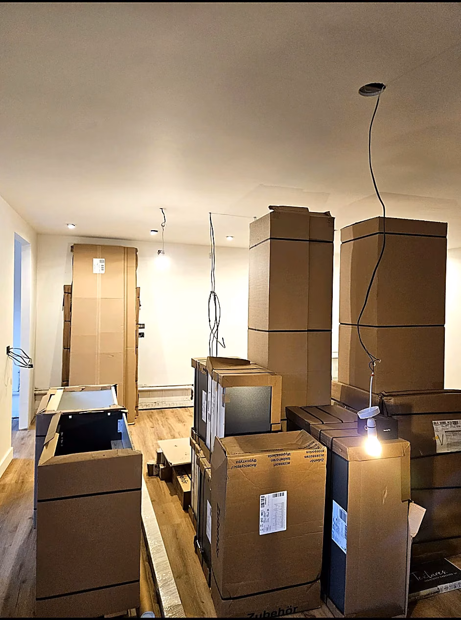 Kitchen refurbishment in progress with cabinetry, boxed materials and temporary pendant lighting